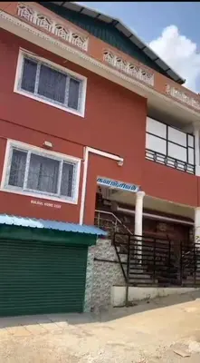 a red building with a garage in front of it at Bull Bull Homestay in Ooty