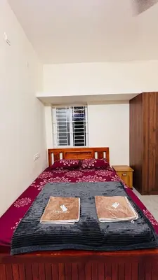 a bedroom with a large bed with a red bedspread at Ashley Homestay 2BHK Codissia, Airport, Tidel Park in Coimbatore