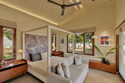 a bedroom with a bed and a couch and windows at SaffronStays Chandra Amara in Bengaluru