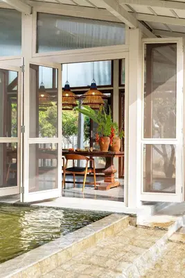 a porch with sliding glass doors and a table with plants at SaffronStays Chandra Amara in Bengaluru