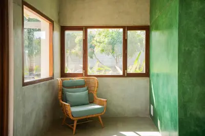 a wicker chair sitting in a room with windows at SaffronStays Chandra Amara in Bengaluru