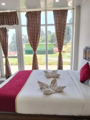 a bedroom with a bed with a large window at TULIPS VILLAGE RESORTS - A Valley View Abode in Ooty