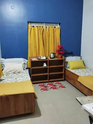 a bedroom with two beds and a yellow curtain at K square in Coimbatore