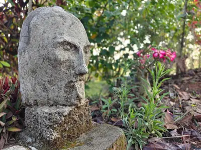 a statue of a head in a garden at spiritofthewild in Attappādi