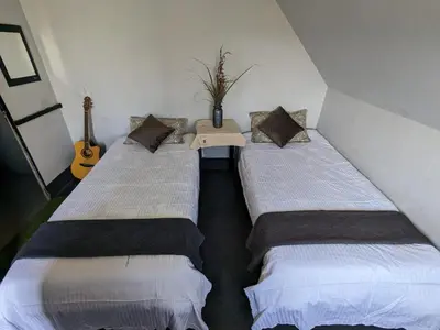 two beds in a room with a table and a guitar at spiritofthewild in Attappādi
