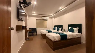 a hotel room with two beds and a television at Ellora grand hotel in Kozhikode