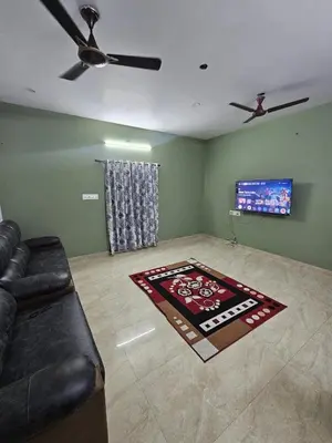 a living room with a couch and a flat screen tv at Home in Pollachi in Pollāchi