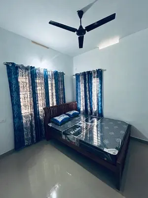 a bed in a room with a ceiling fan at VYSHNAVI 2BHK AC Apartment in Thanniyam