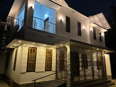a large white house with a balcony at night at Nilavu Homes Retreat in Wayanad