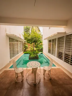 a patio with two chairs and a table and a pool at Akshaya Homestay in Trichūr