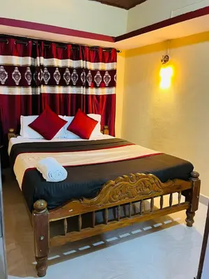 a bed with red pillows in a room with a curtain at Coorgkushihomestay in Madikeri