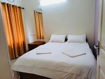 a bedroom with a white bed with two towels on it at very spacious furnished apartment in Guruvāyūr