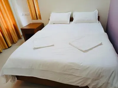 a large white bed with white sheets and pillows at very spacious furnished apartment in Guruvāyūr