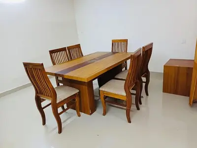 a wooden table with four chairs and a wooden box at very spacious furnished apartment in Guruvāyūr