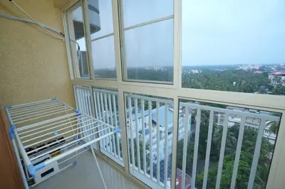 a room with a balcony with a large window at Janaki Heavens, 1 BHK Apartment in Guruvāyūr