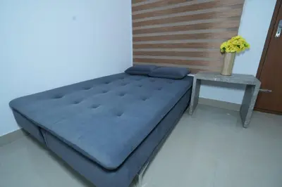 a bed in a room with a table at Janaki Heavens, 1 BHK Apartment in Guruvāyūr