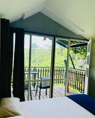 a bedroom with a bed and a view of a deck at Hill wood nature touch resort in Pinangode