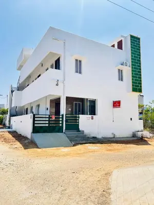 a white building with green doors on the side of it at AAG Pride serviced apartments in Pollāchi