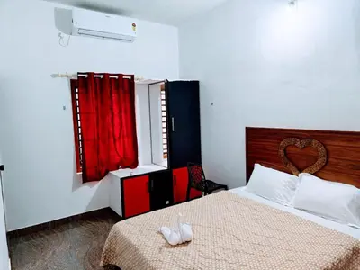 a bedroom with a bed and a red window at Flavoury Restaurant & Rooms in Paithalmala