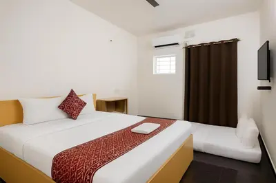 a bedroom with a large white bed and a television at Mysore Couple Friendly at 999 in Mysore