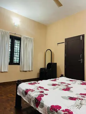 a bedroom with a bed with red flowers on it at Chirakkal Heritage Luxury Homestay in Manjeri