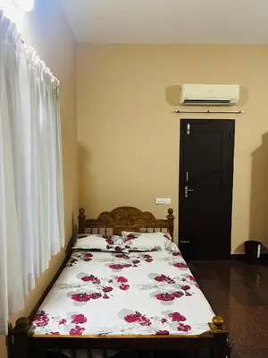 a bedroom with a bed with red flowers on it at Chirakkal Heritage Luxury Homestay in Manjeri