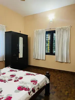 a bedroom with a bed and two windows at Chirakkal Heritage Luxury Homestay in Manjeri
