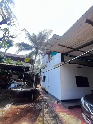 a building with a tub next to a palm tree at Ashique holiday home in Padinjarathara