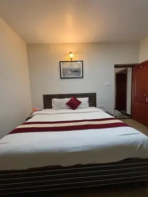 a bedroom with a large bed with a red pillow at Blessing holidays ooty in Ooty