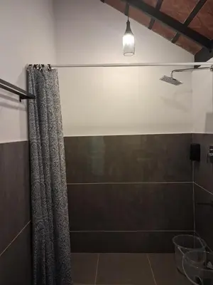 a bathroom with a shower with a shower curtain at Vidman Homey Huts in Tindummal