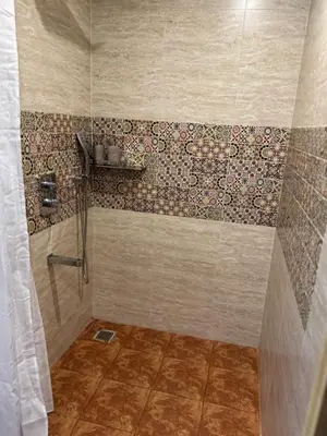 a bathroom with a shower with a tiled wall at Bhoomi in Mysore
