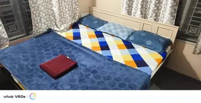 a bed with a blue comforter and pillows on it at Hazel's ELiTE Homestay 3BHK in Mysore