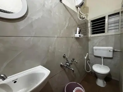 a bathroom with a sink and a toilet and a window at Hazel's ELiTE Homestay 2bhk in Mysore