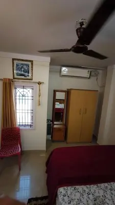 a bedroom with a bed and a ceiling fan at Steeva Guest house in Mysore