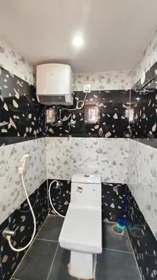 a small bathroom with a toilet with black and white wallpaper at Steeva Guest house in Mysore