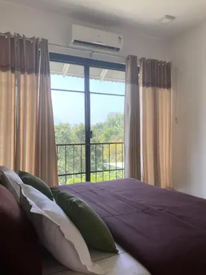 a bedroom with a bed and a large window at Homestay Namaha in Meppādi