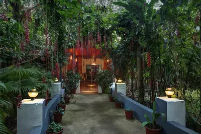a hallway in a garden with trees and plants at Gokulam Grand Resort & Spa, Coorg in Kushālnagar