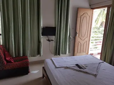 a bedroom with a bed and a chair and a door at Blue Stones Service Apartment in Coimbatore