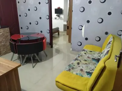 a living room with a yellow chair and a table at Blue Stones Service Apartment in Coimbatore