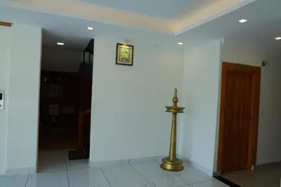 a hallway with a white wall and a gold pole at Anna Residency in Nedumbassery