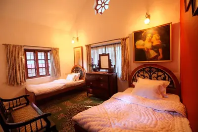 a bedroom with two beds and a dresser and a mirror at The Red House in Ooty