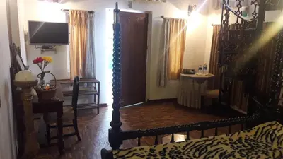 a room with a bed and a television in it at The Red House in Ooty