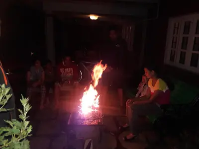 a group of people sitting around a fire at The Red House in Ooty