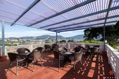 a patio with tables and chairs on a balcony at Zostel Ooty in Ooty