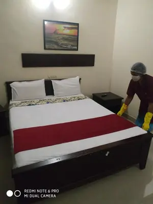 a man is making a bed in a room at Orison Residency Hotel in Kunnamkulam