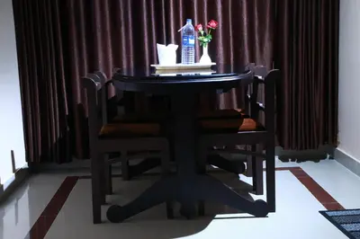 a black table with a bottle of water and flowers on it at Orison Residency Hotel in Kunnamkulam