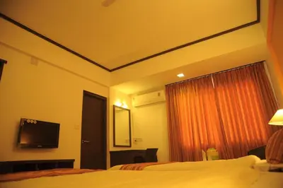 a hotel room with a bed and a flat screen tv at Sugam Hotel Pvt Ltd in Coimbatore
