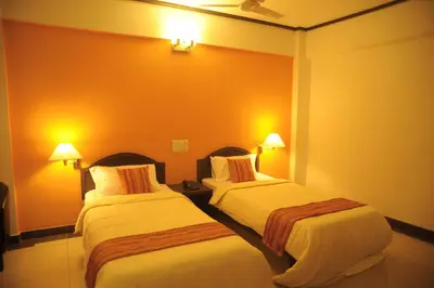 two beds in a hotel room with orange walls at Sugam Hotel Pvt Ltd in Coimbatore