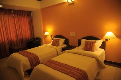 a hotel room with two beds and two lamps at Sugam Hotel Pvt Ltd in Coimbatore