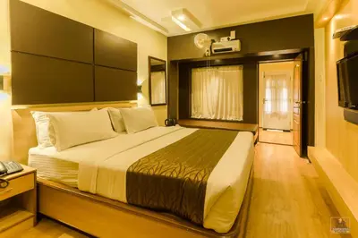 a bedroom with a large bed and a television at Darshan Hotel in Ooty